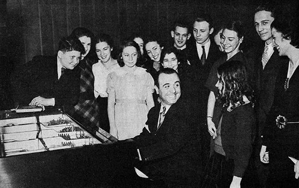 一名男子在钢琴旁与学生们聚在一起
