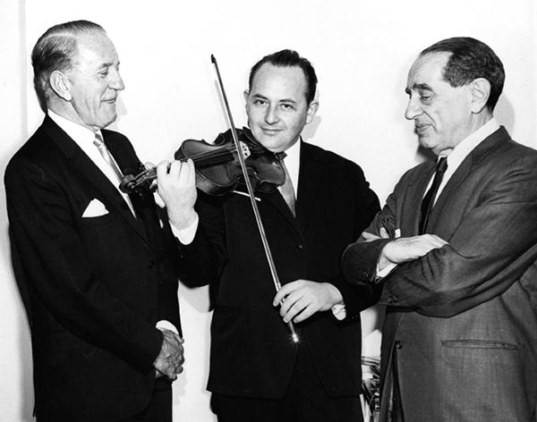 三个西装革履的男人，一个在拉小提琴